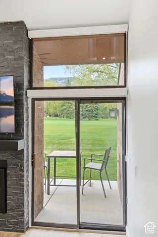 Sliding glass door leading to a concrete patio, featuring an overhead transom window with a privacy shade