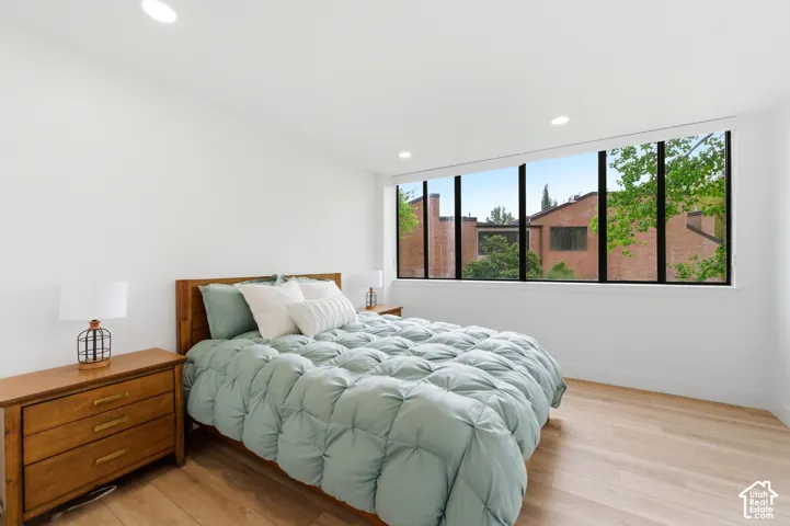 Expansive window wall with black framing, recessed ceiling lighting, light wood-finish flooring, and white painted walls