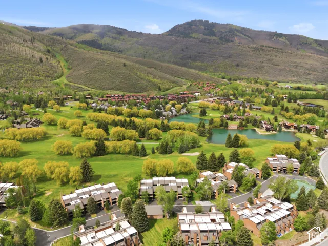 Expansive golf course property with multiple water features, mature trees, and surrounding mountainous terrain