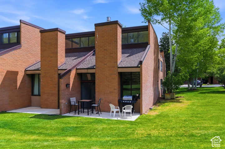Brick exterior with multiple chimneys, sloped shingle roofing, and upper-level transom windows