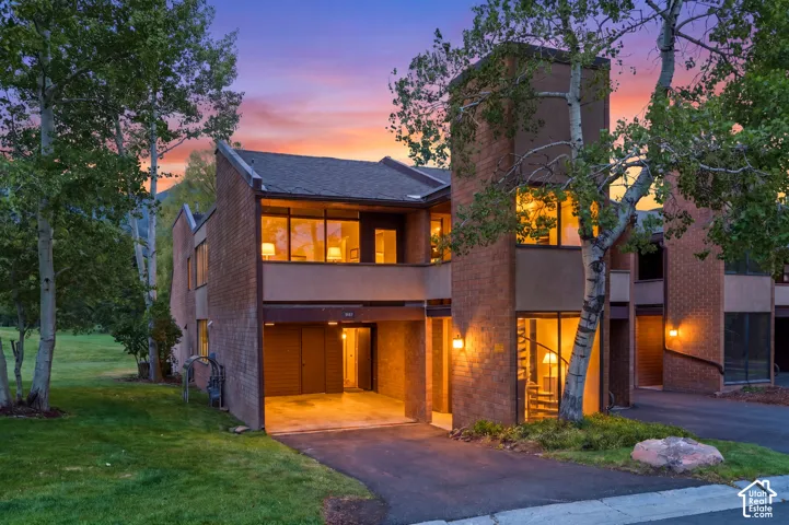 Brick exterior with large windows, covered parking, and an asphalt driveway