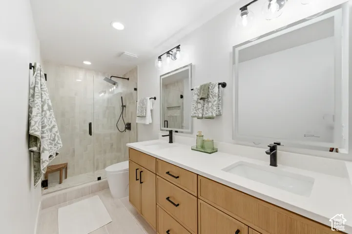 Dual vanity with white countertops, light wood-finish cabinetry, and matte black fixtures