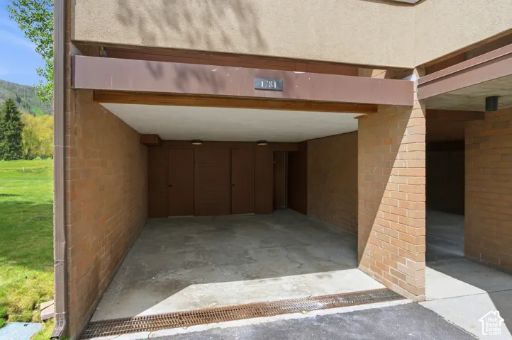 Covered parking space with concrete flooring, brick walls, and integrated lighting