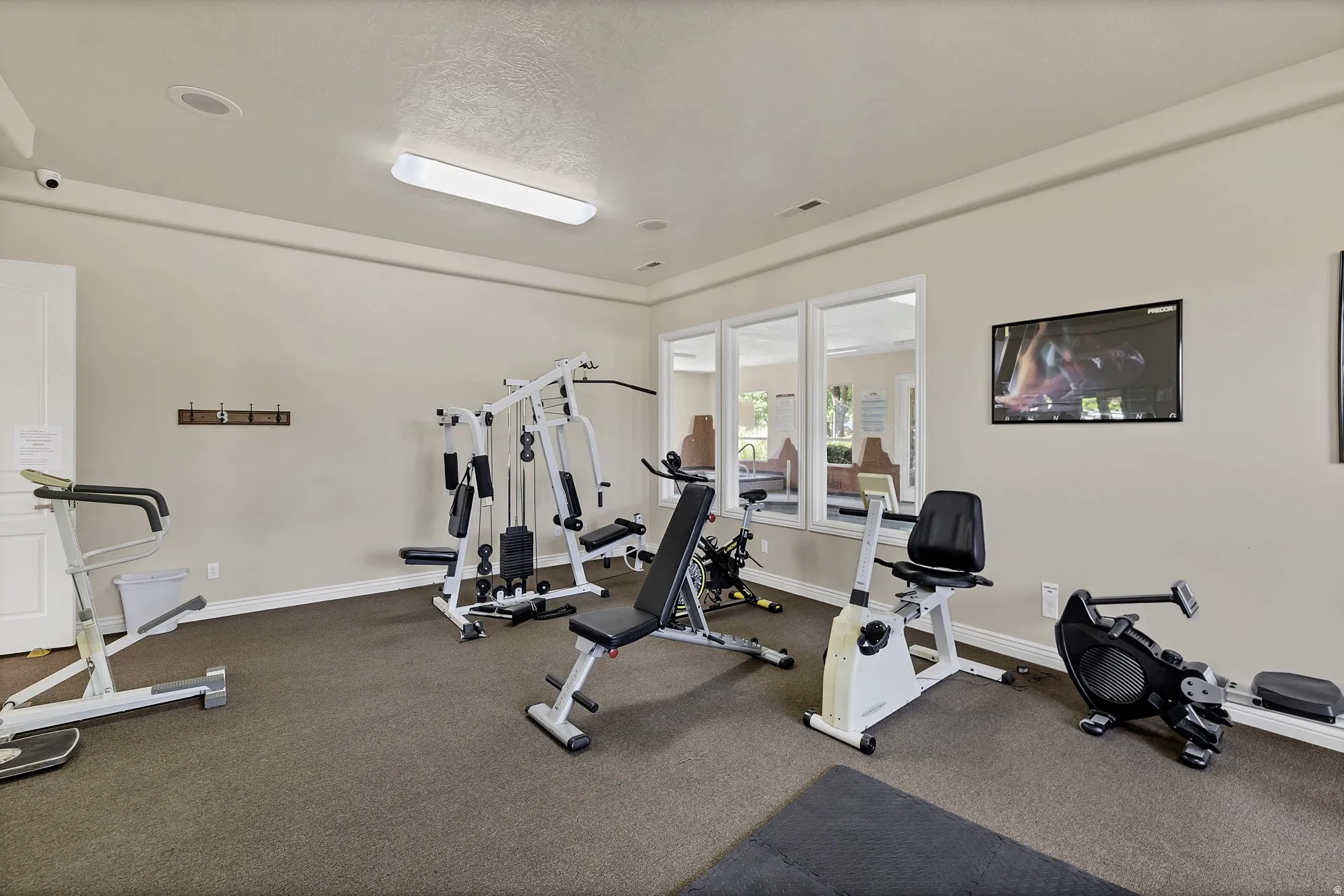 Fitness room with neutral wall paint, carpet flooring, recessed lighting, and a wall-mounted television