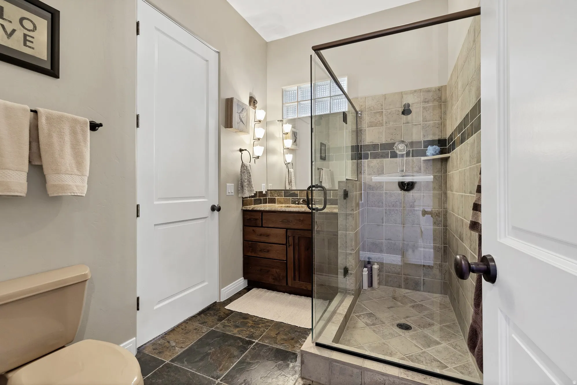 Walk-in shower with clear glass enclosure and tiled walls