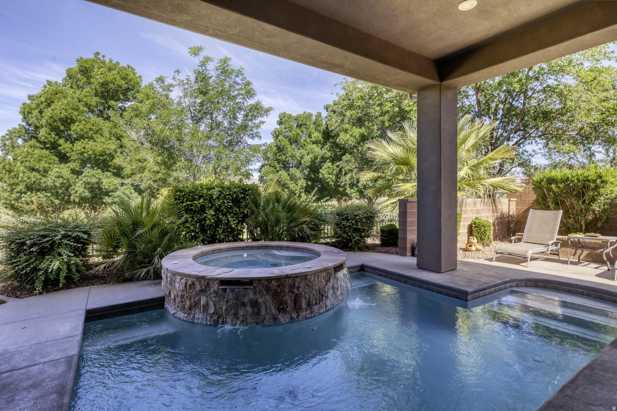 Covered patio overlooking a pool with an integrated, stone-clad spa