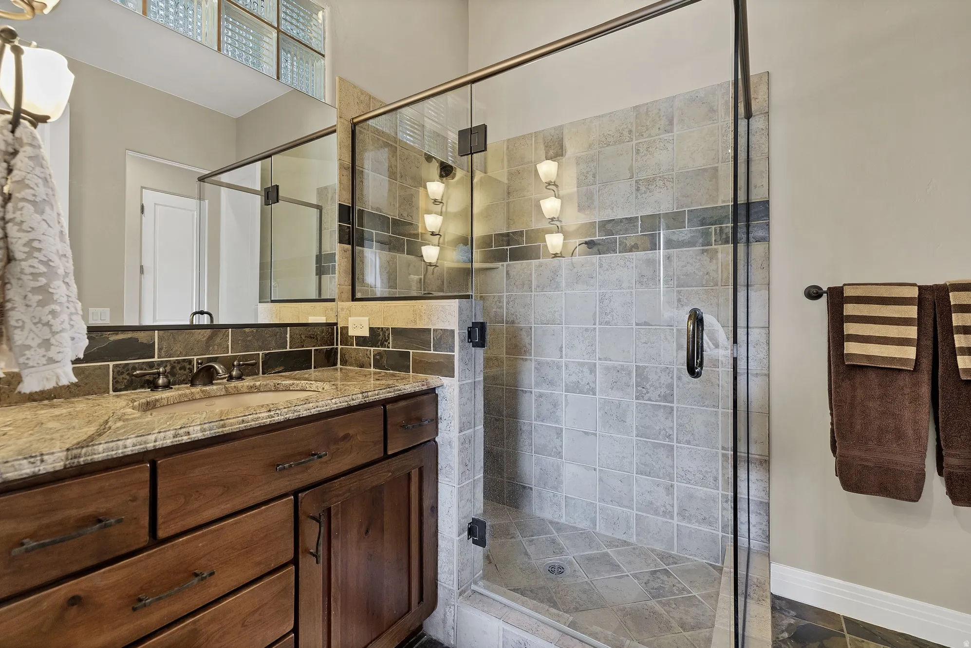 Glass-enclosed shower with tiled walls and a decorative accent band