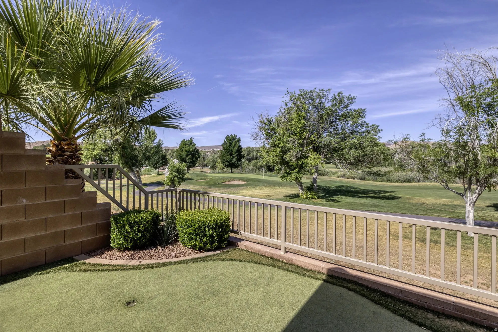 Putting green with a single hole set against a backdrop of mature trees and open green space