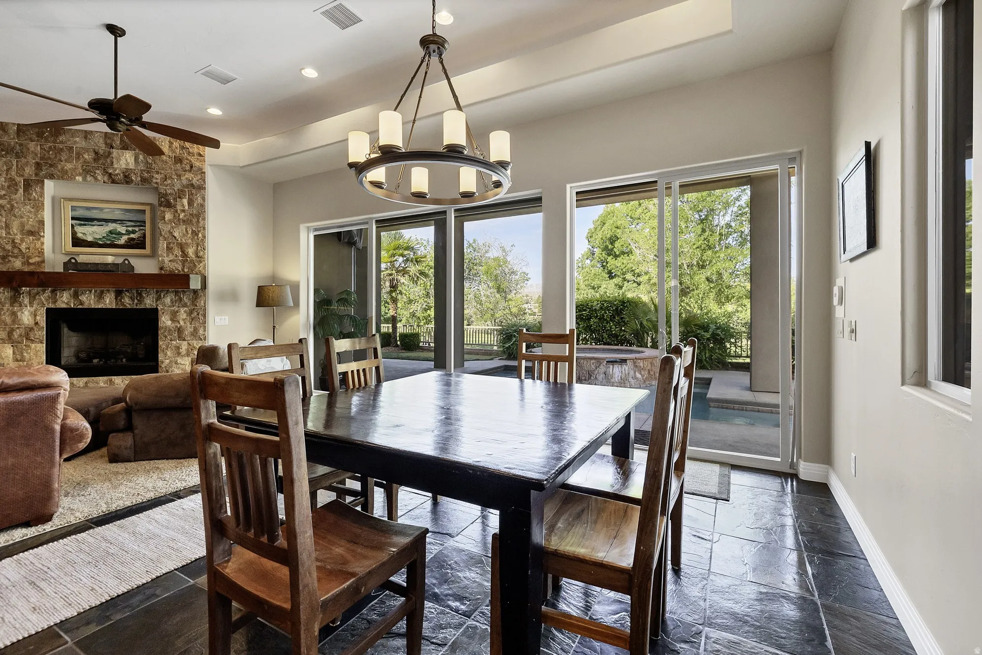 Open-concept living area featuring a stone-clad fireplace with a wood mantle, recessed lighting, and a ceiling fan