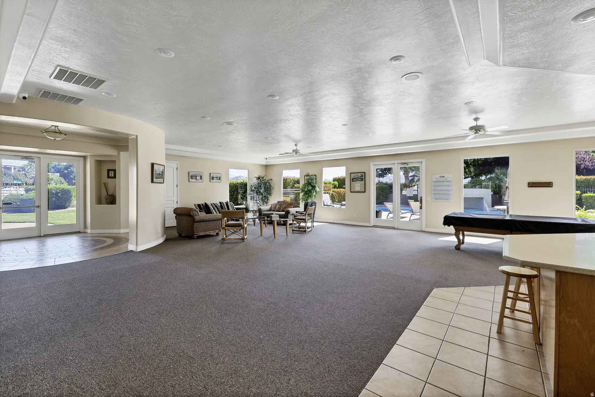 Spacious common area featuring broad windows, multiple exterior access points, recessed lighting, and ceiling fans