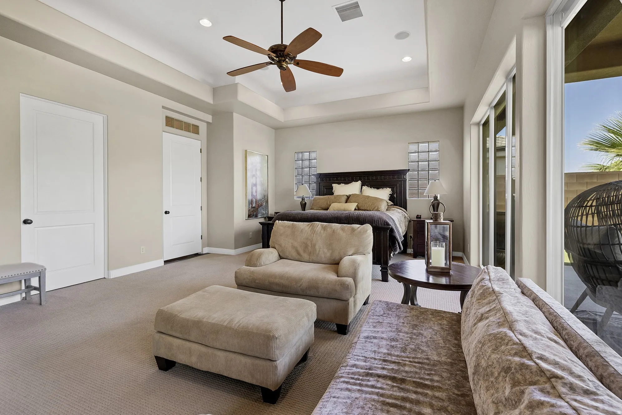 Spacious bedroom with tray ceiling, recessed lighting, and a ceiling fan