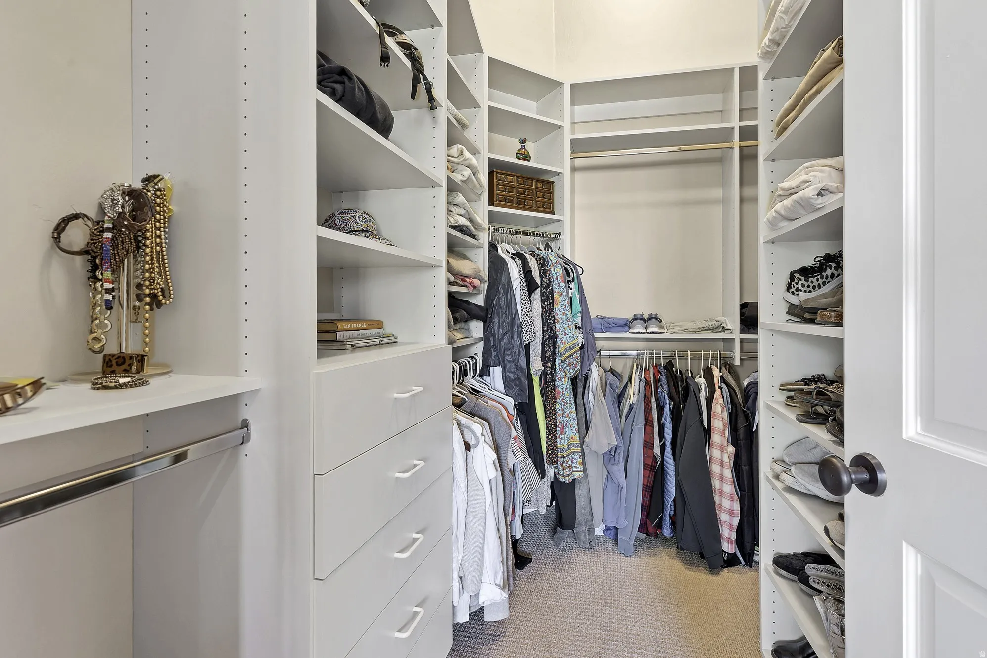 Custom-designed walk-in closet featuring built-in shelving, integrated drawers with modern pulls, and multiple hanging rods