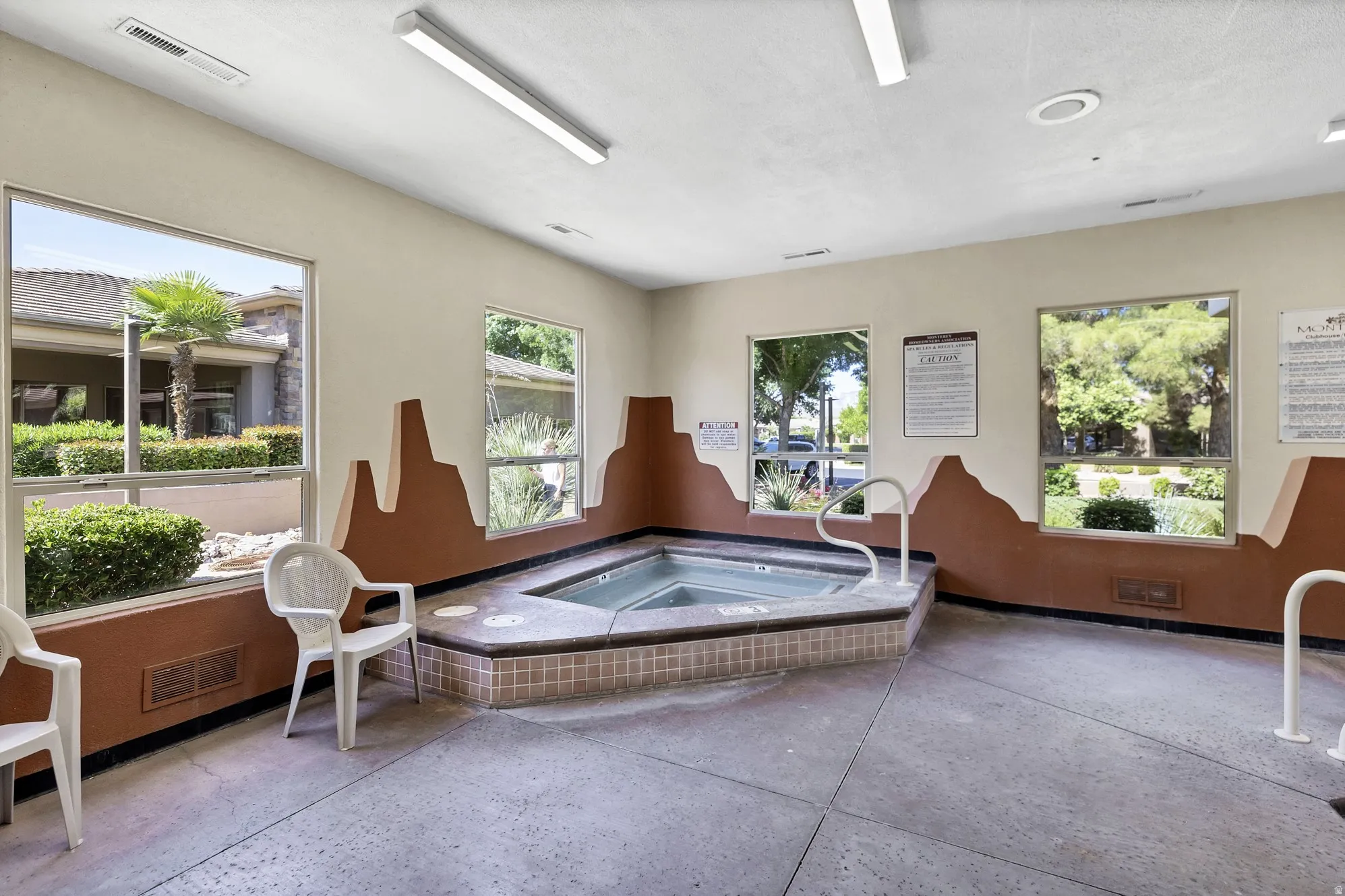 Indoor spa area featuring a tiled hot tub with access rails