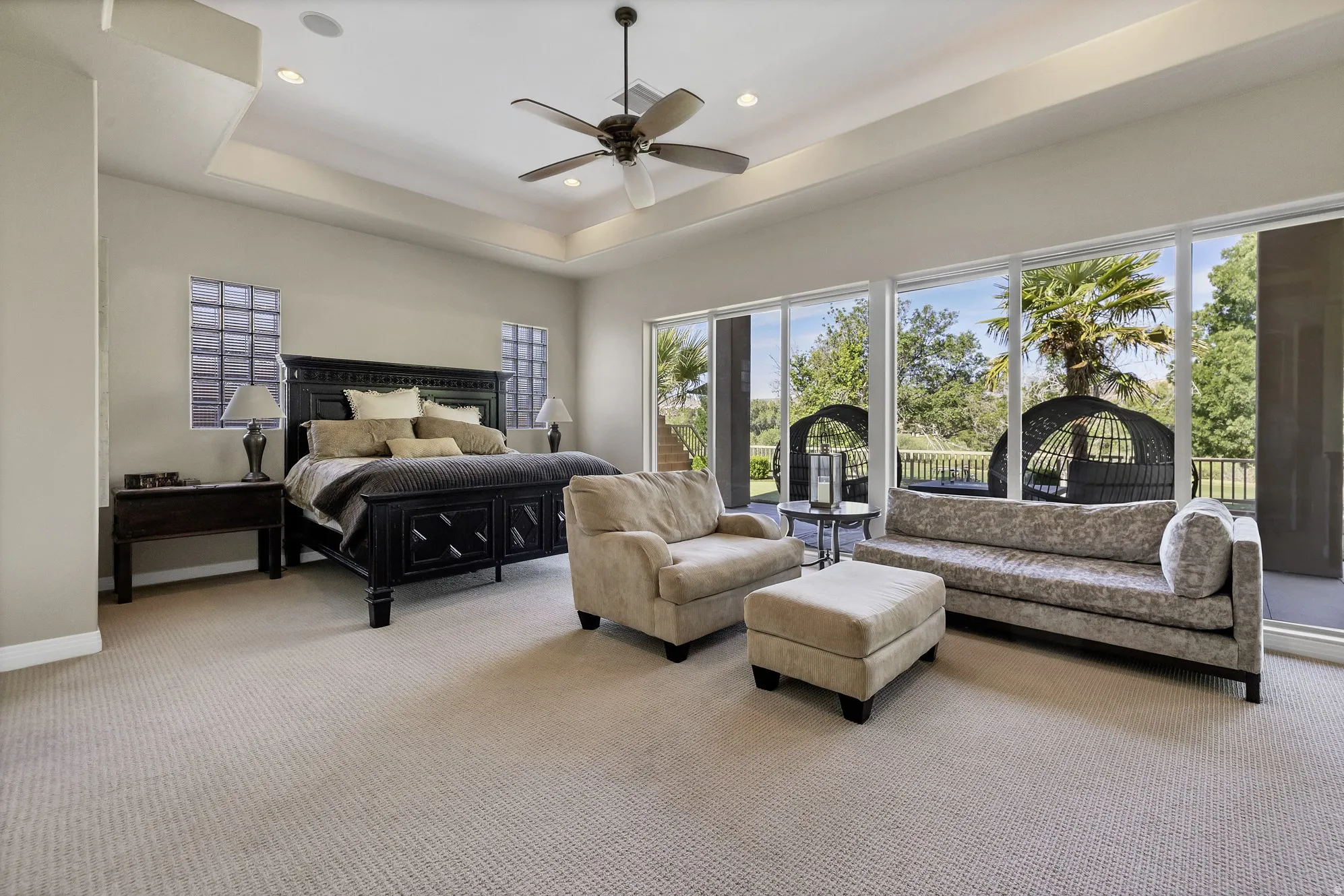 Carpeted bedroom featuring a tray ceiling with recessed lighting and a ceiling fan