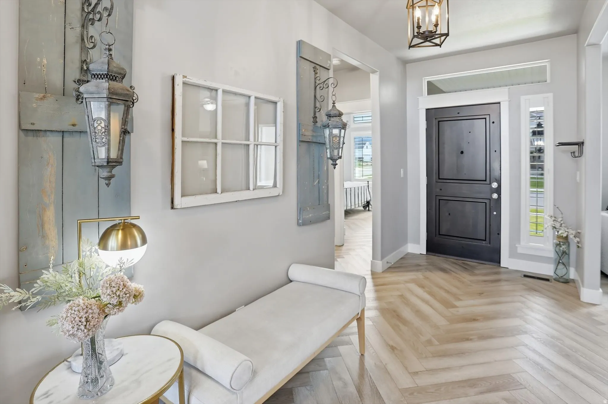 Inviting entry featuring herringbone wood-finish flooring, a substantial dark entry door with side lites and transom window, and an overhead lantern fixture