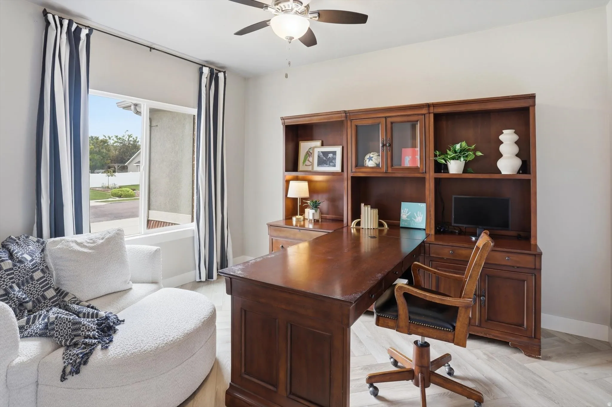 Room featuring wood-finish herringbone flooring, a large window, and a ceiling fan