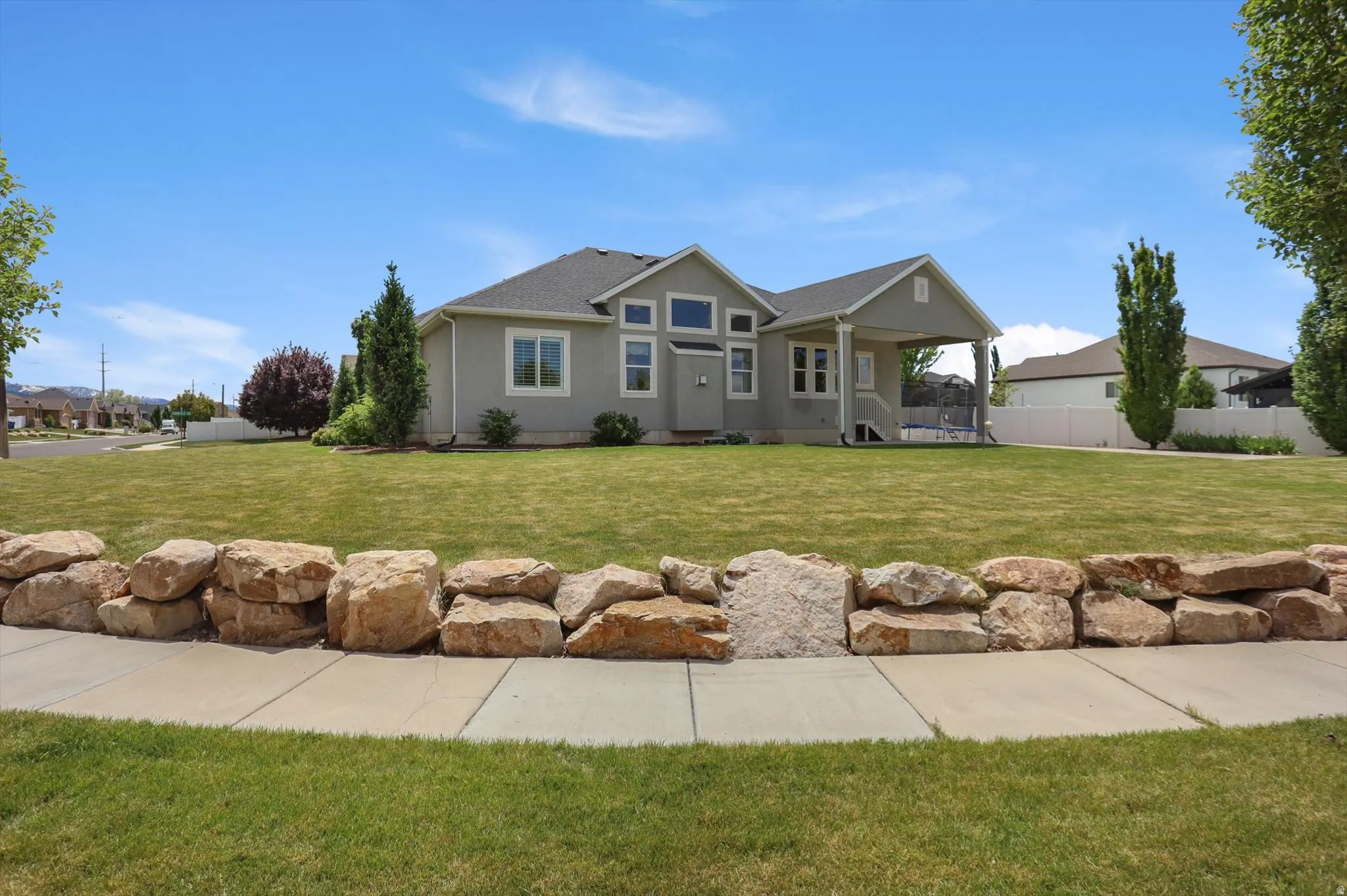 Ranch-style residence featuring a prominent covered porch, multiple large windows, and a grey exterior