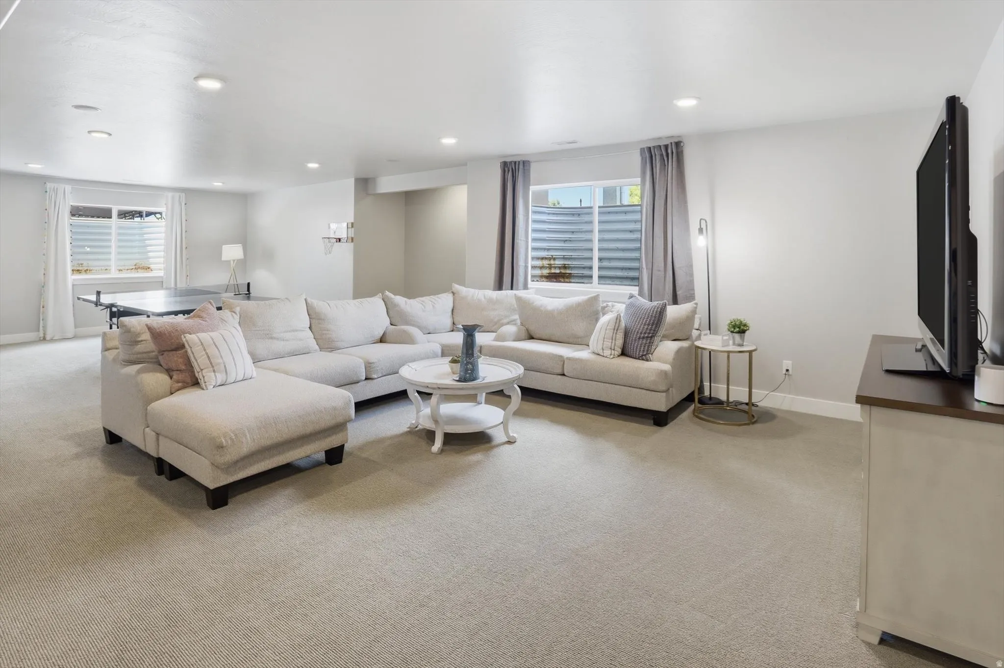 Spacious living area featuring light-toned carpeting and recessed lighting