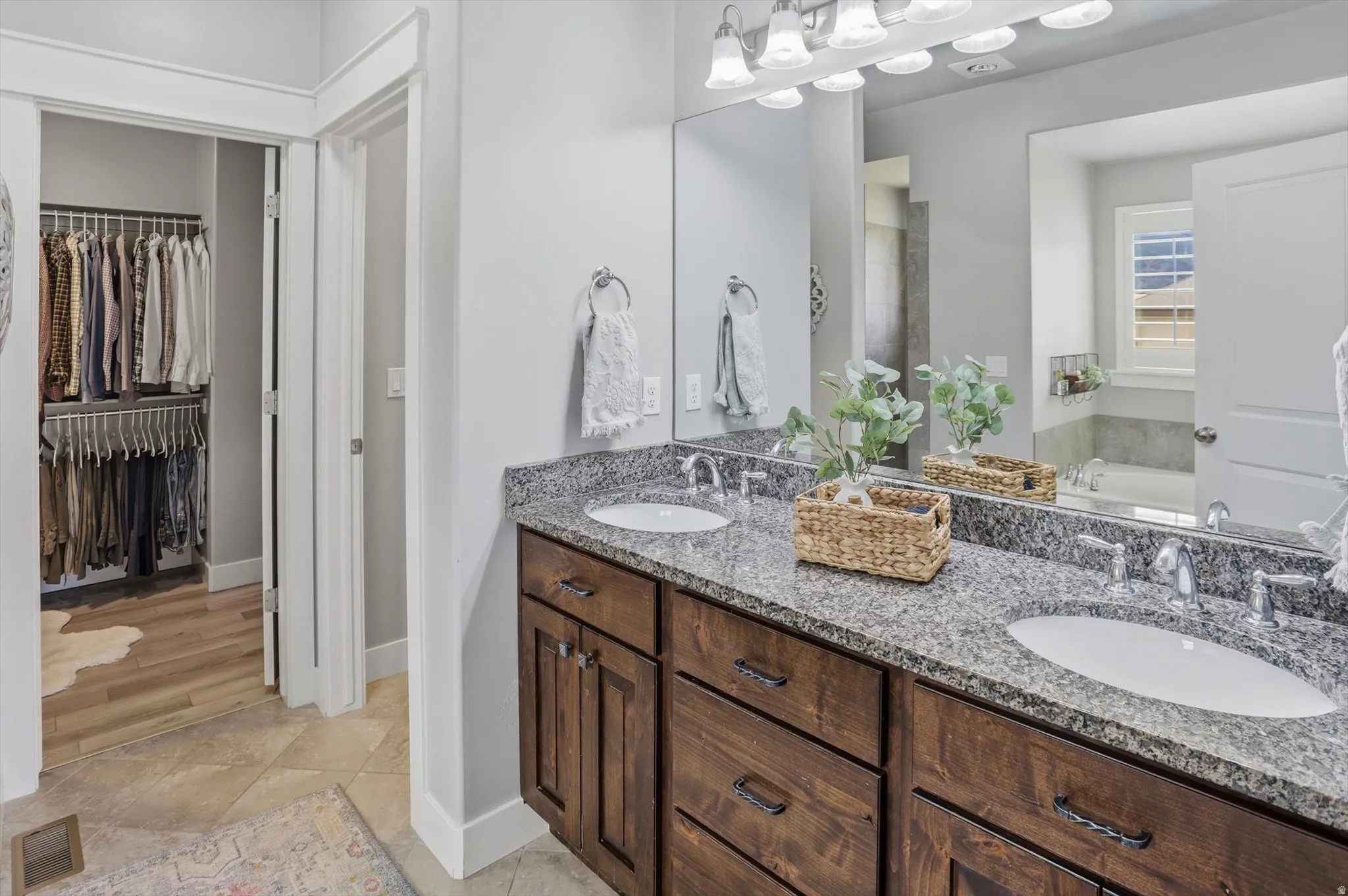 Master Bathroom featuring a double vanity with wood-finish cabinetry, granite countertops, and two undermount sinks