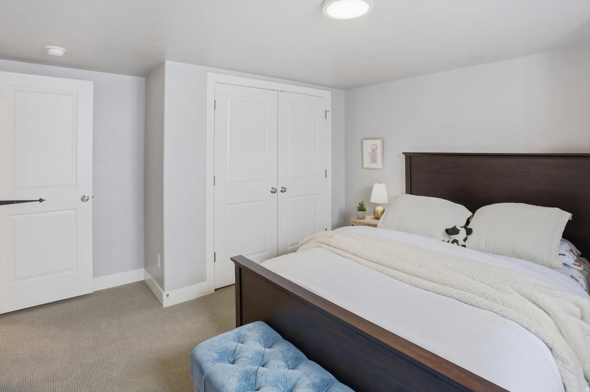 Bedroom #4 Carpeted room featuring a dark wood bed frame, white paneled doors, built-in closet with double doors, and a ceiling-mounted light fixture
