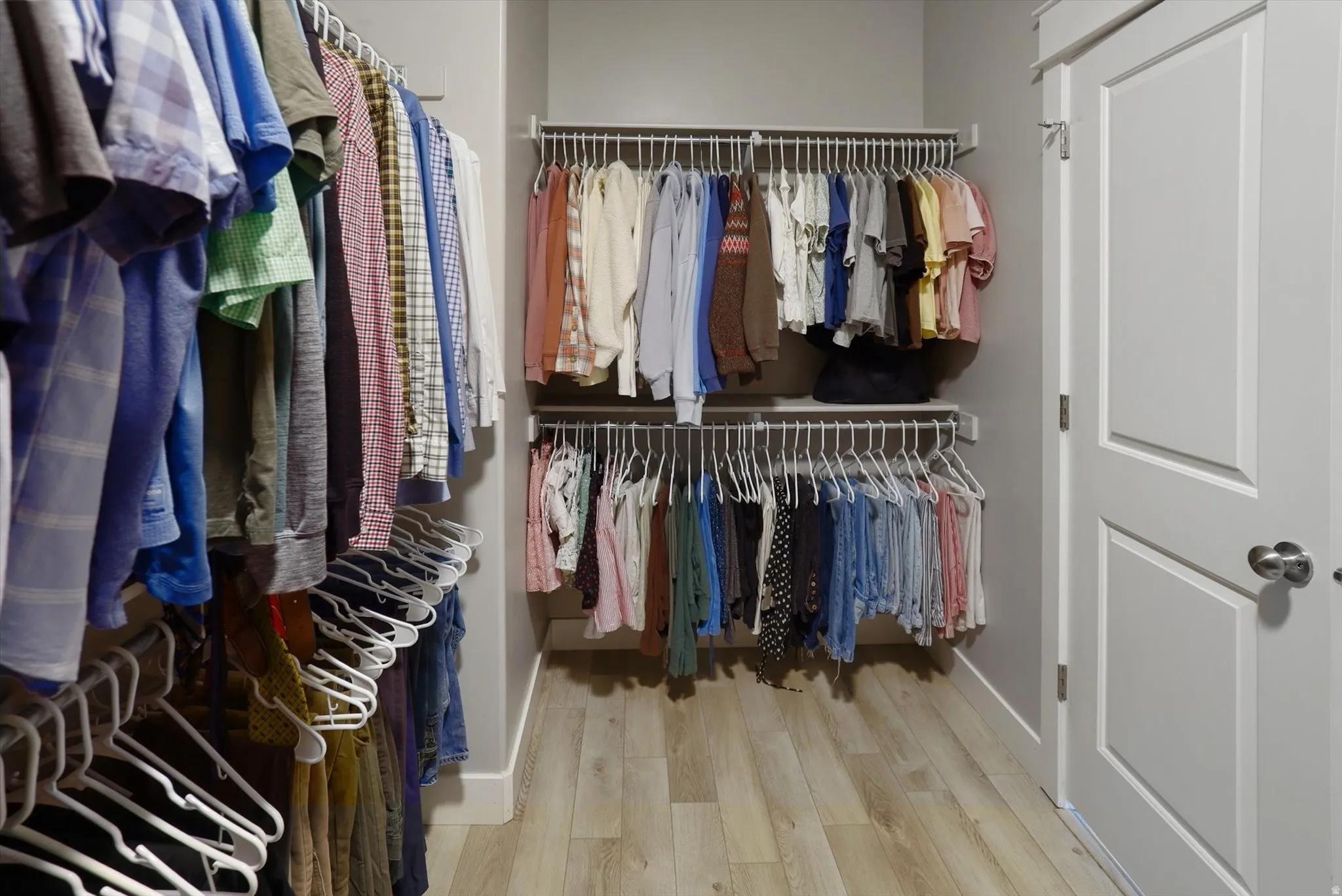 Master Walk-in closet featuring light wood-finish flooring, white wire shelving, and a panel-style interior door with a brushed nickel knob