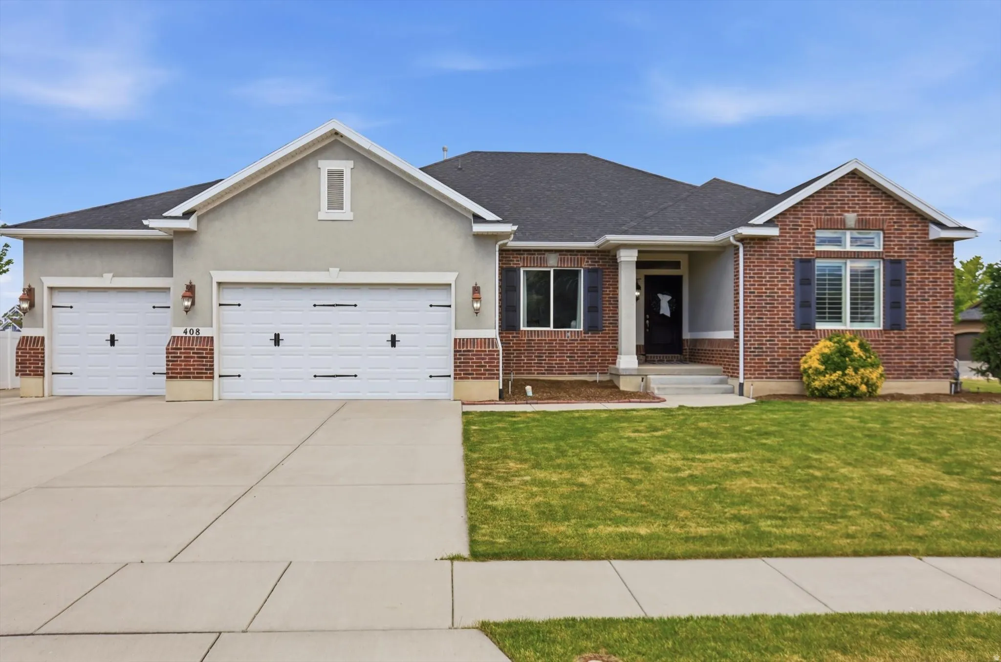 Brick and stucco exterior with a dark shingle roof