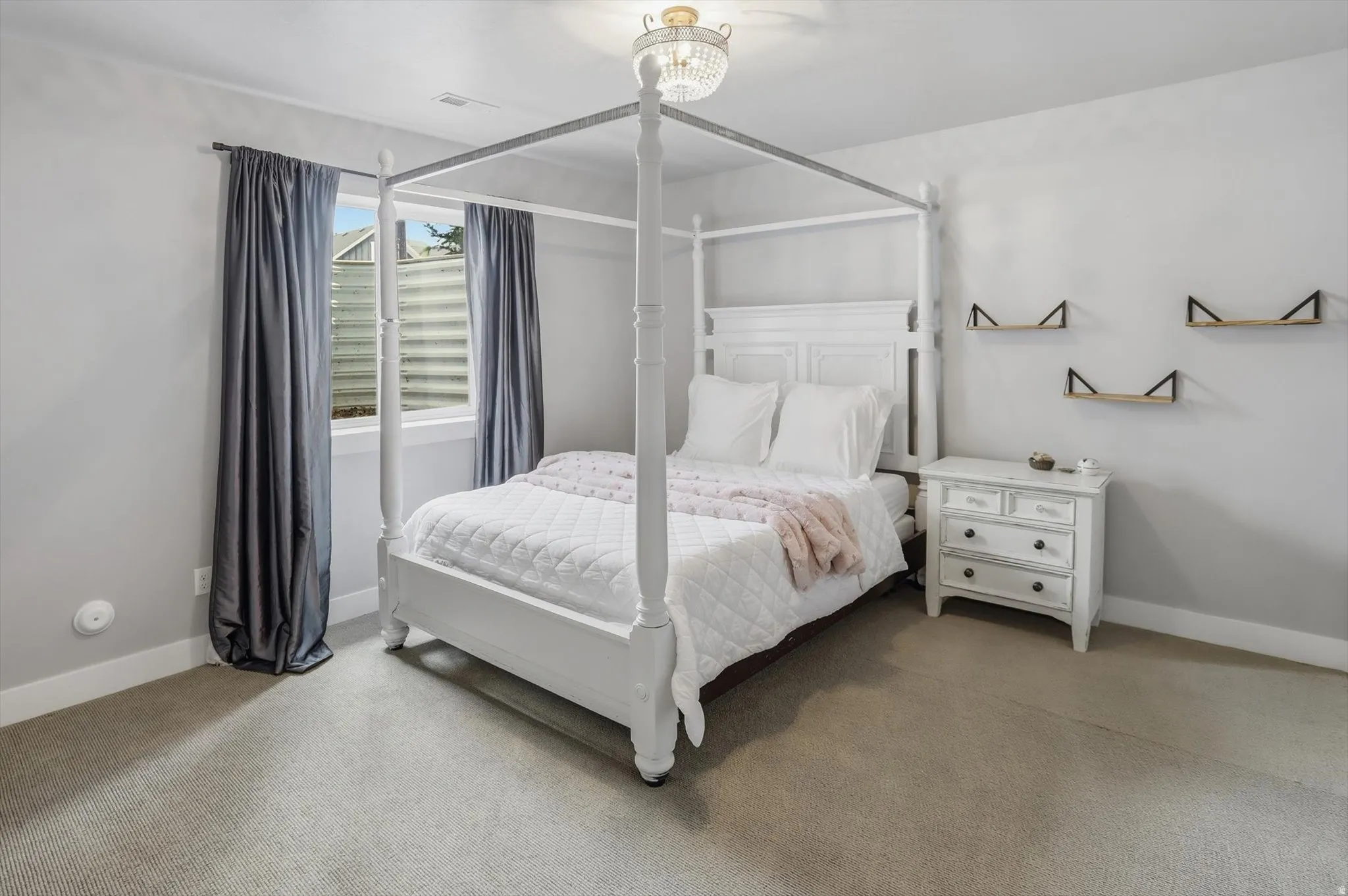 Bedroom #3 featuring light gray wall paint, light-colored carpeting, a window with white trim, and a ceiling-mounted light fixture