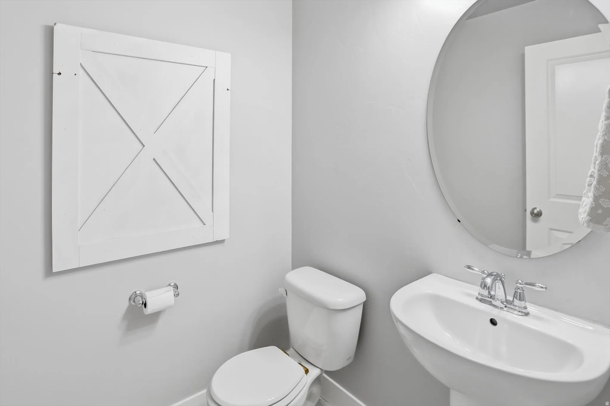 Half  bathroom featuring a white pedestal sink with chrome faucet, a matching toilet, and a large oval mirror