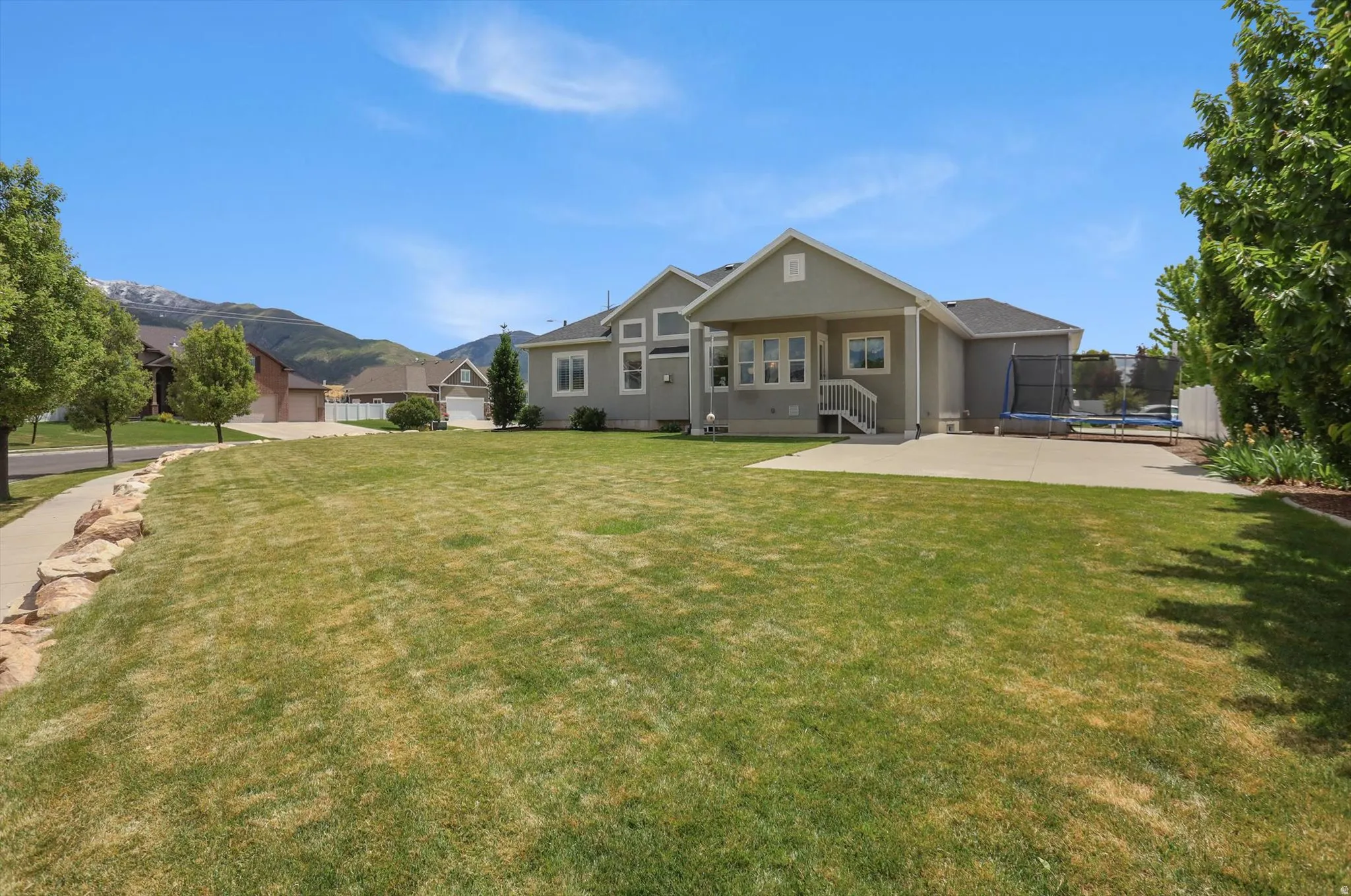 Spacious backyard featuring an extensive lawn and a concrete patio