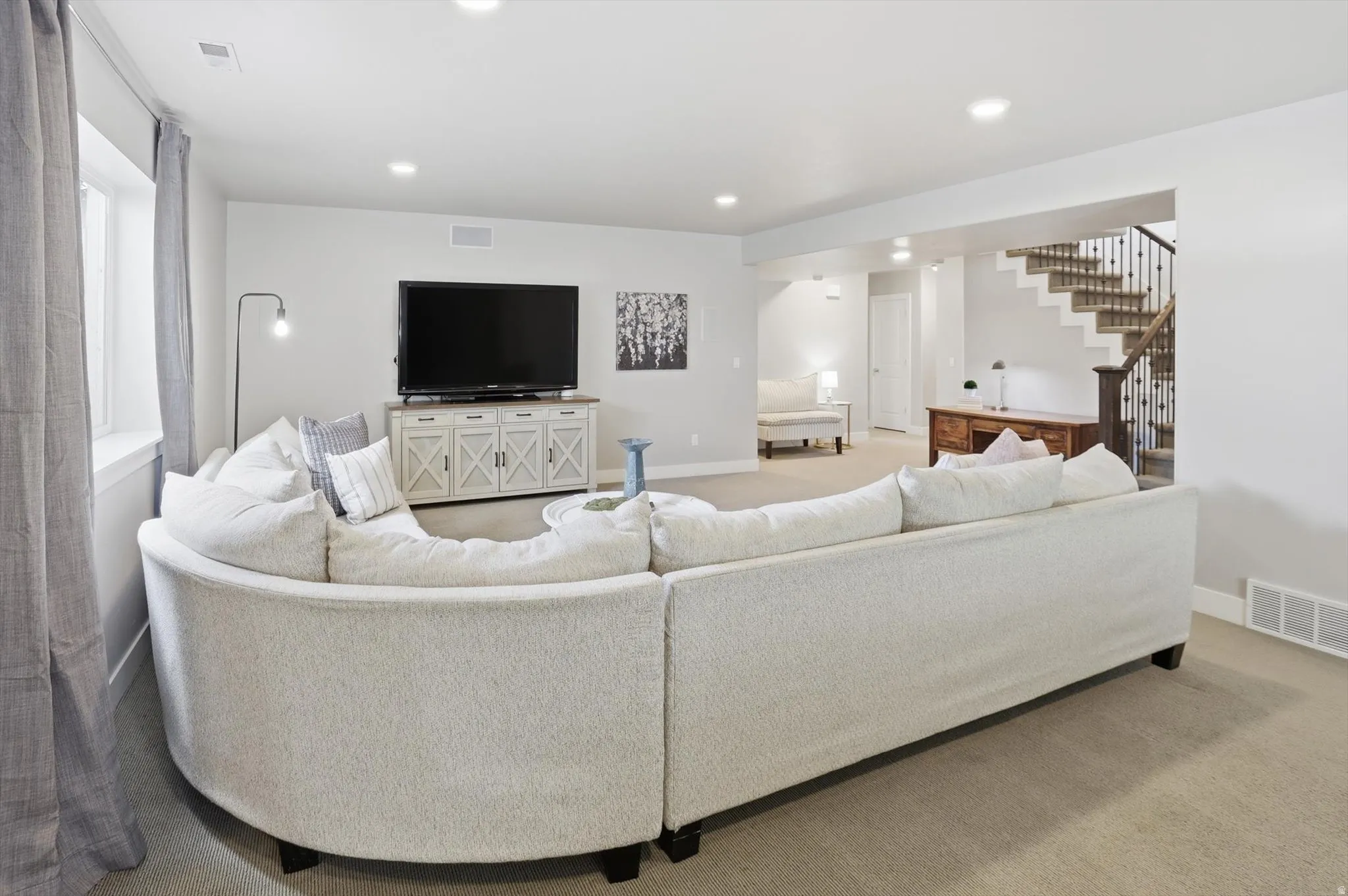 Open-concept living space featuring light-toned carpeting and recessed lighting