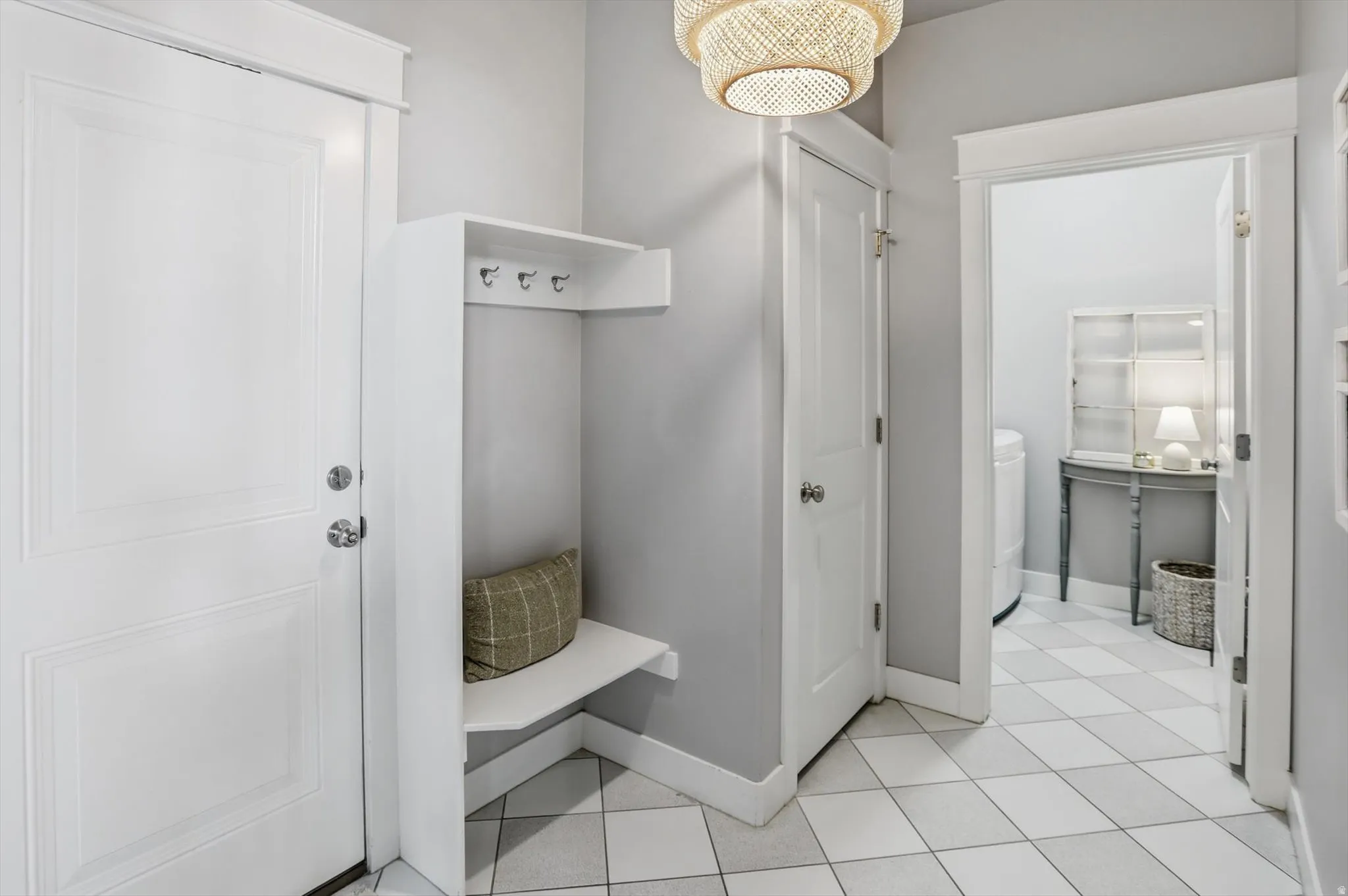 Entryway featuring a built-in bench with coat hooks, white paneled doors, and a decorative light fixture