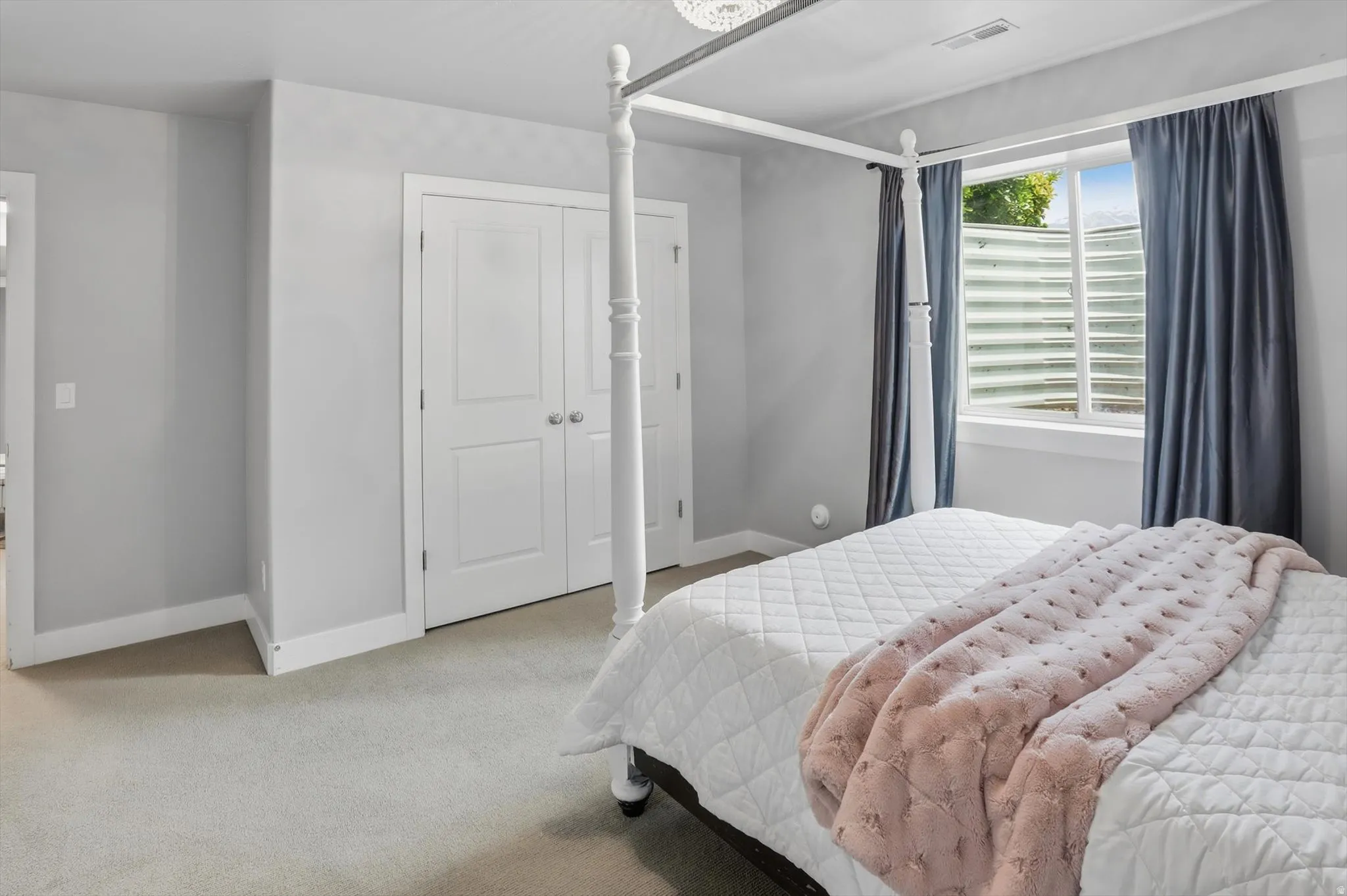 Bedroom #3 Carpeted room featuring a white window frame, white baseboards, and a pair of white bifold closet doors with silver hardware