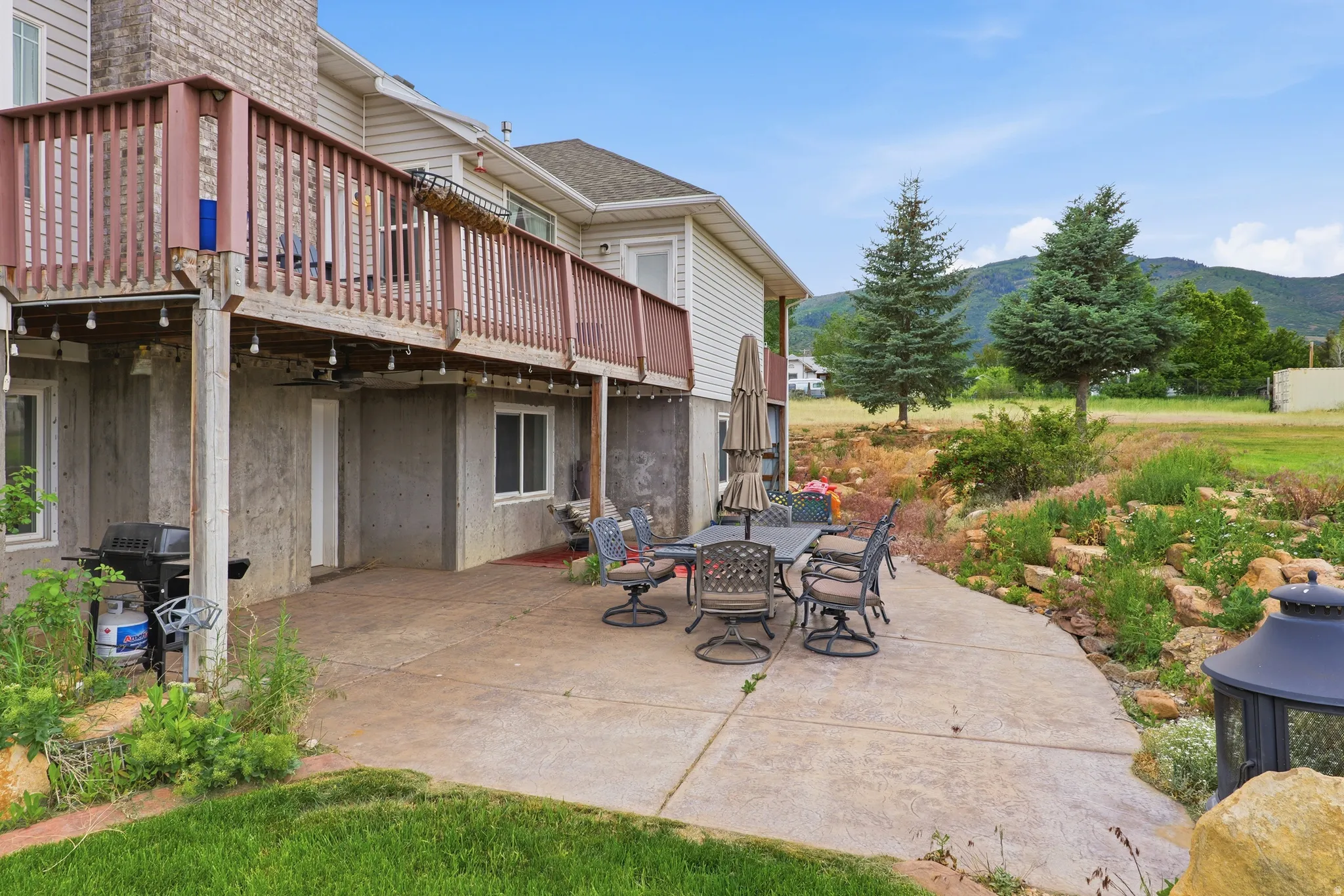 Expansive concrete patio with a tiered, natural rock landscaping feature