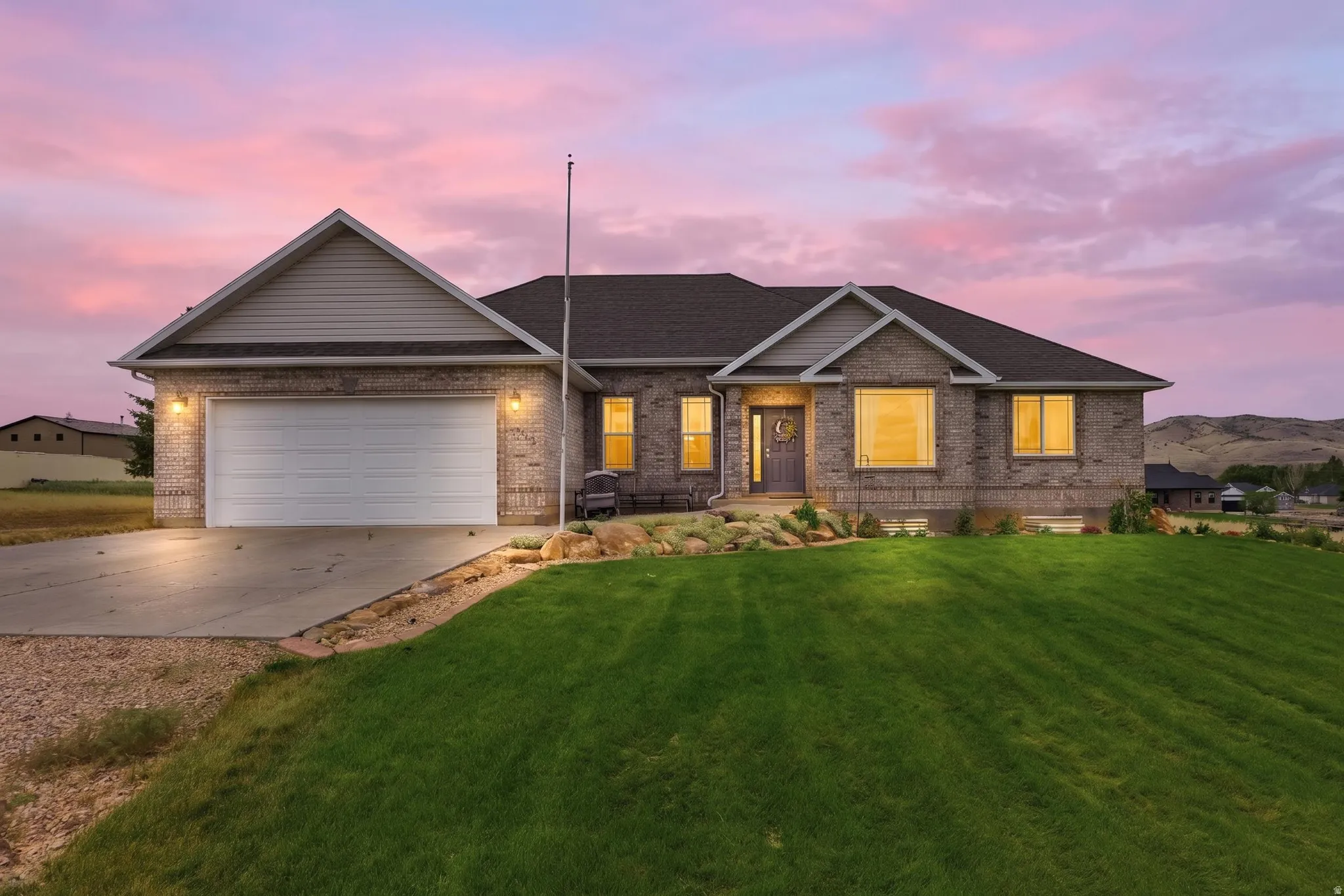 Ranch-style exterior featuring brick veneer, a dark shingle roof, an attached two-car garage, and a manicured front lawn