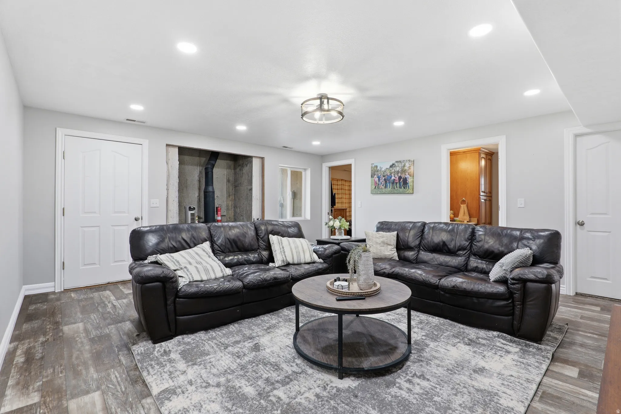 Spacious room featuring wood-finish flooring, recessed lighting, a modern ceiling fixture, and light-toned wall paint