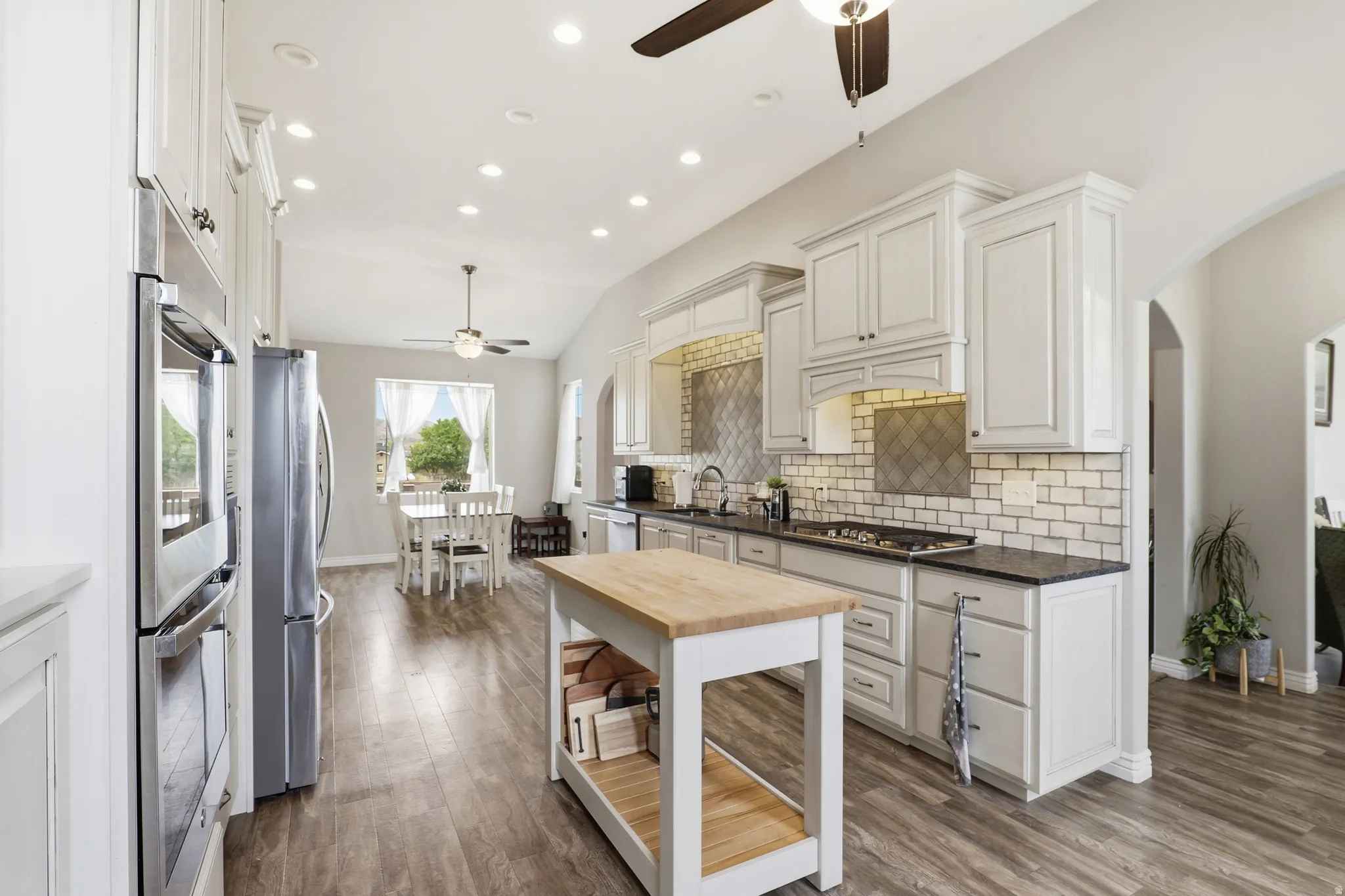 Open-concept kitchen featuring wood-finish flooring, recessed lighting, and a vaulted ceiling with a ceiling fan