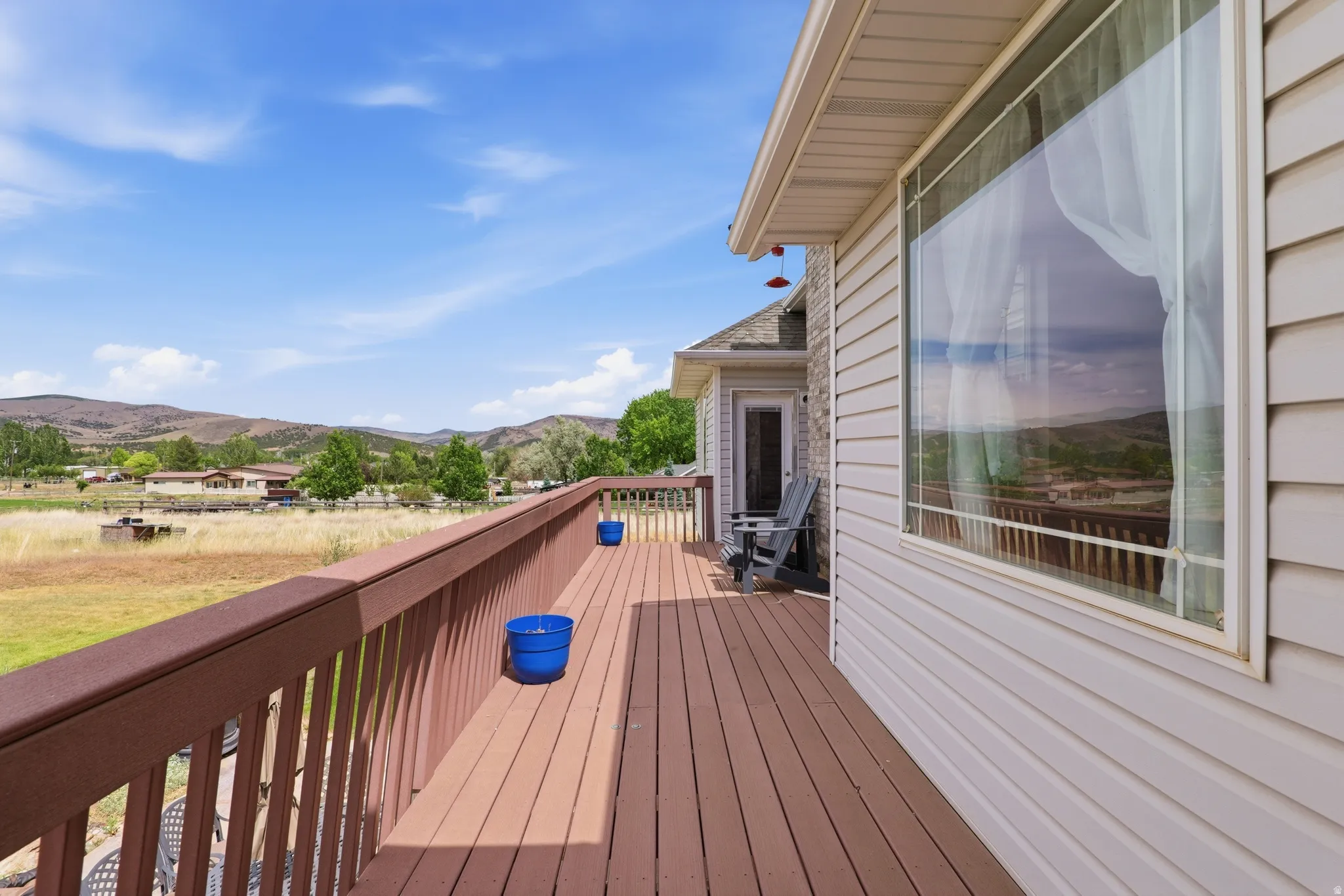 Expansive exterior deck featuring a brown wood-finish surface, matching railing, and a mountain backdrop