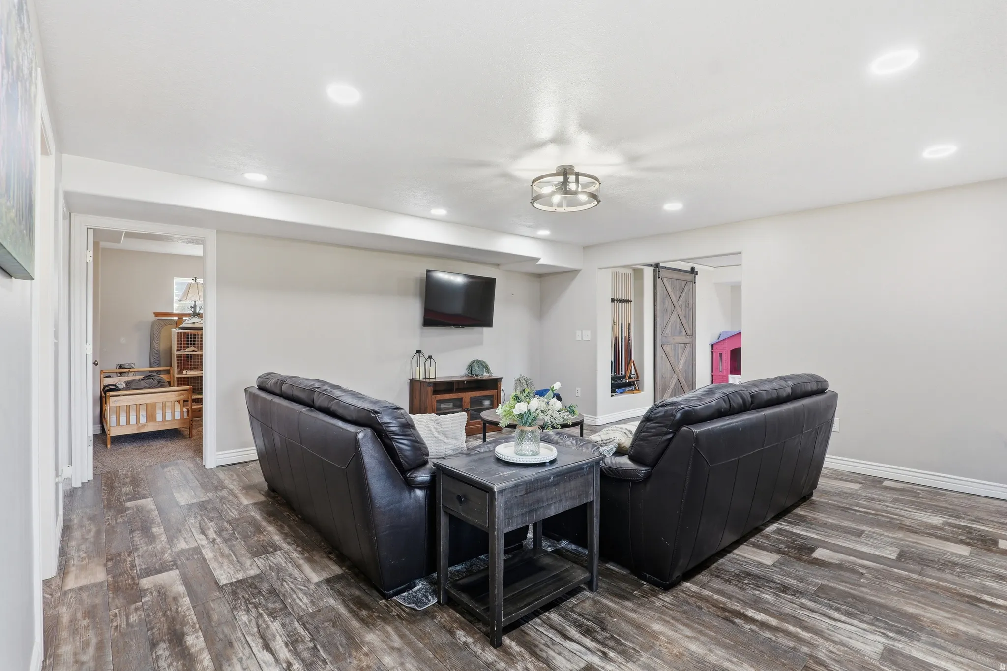 Spacious interior featuring wood-finish flooring, recessed lighting, a modern ceiling light fixture, and light-toned walls
