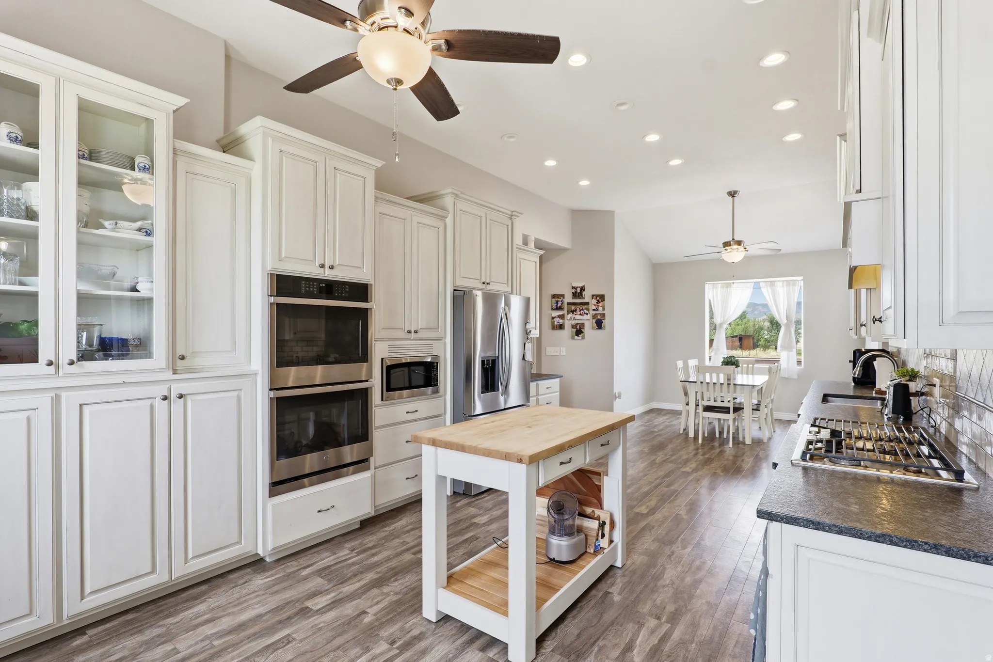 Kitchen featuring white cabinetry, stainless steel double wall ovens, a center island with a wood countertop, wood-finish flooring, and recessed lighting