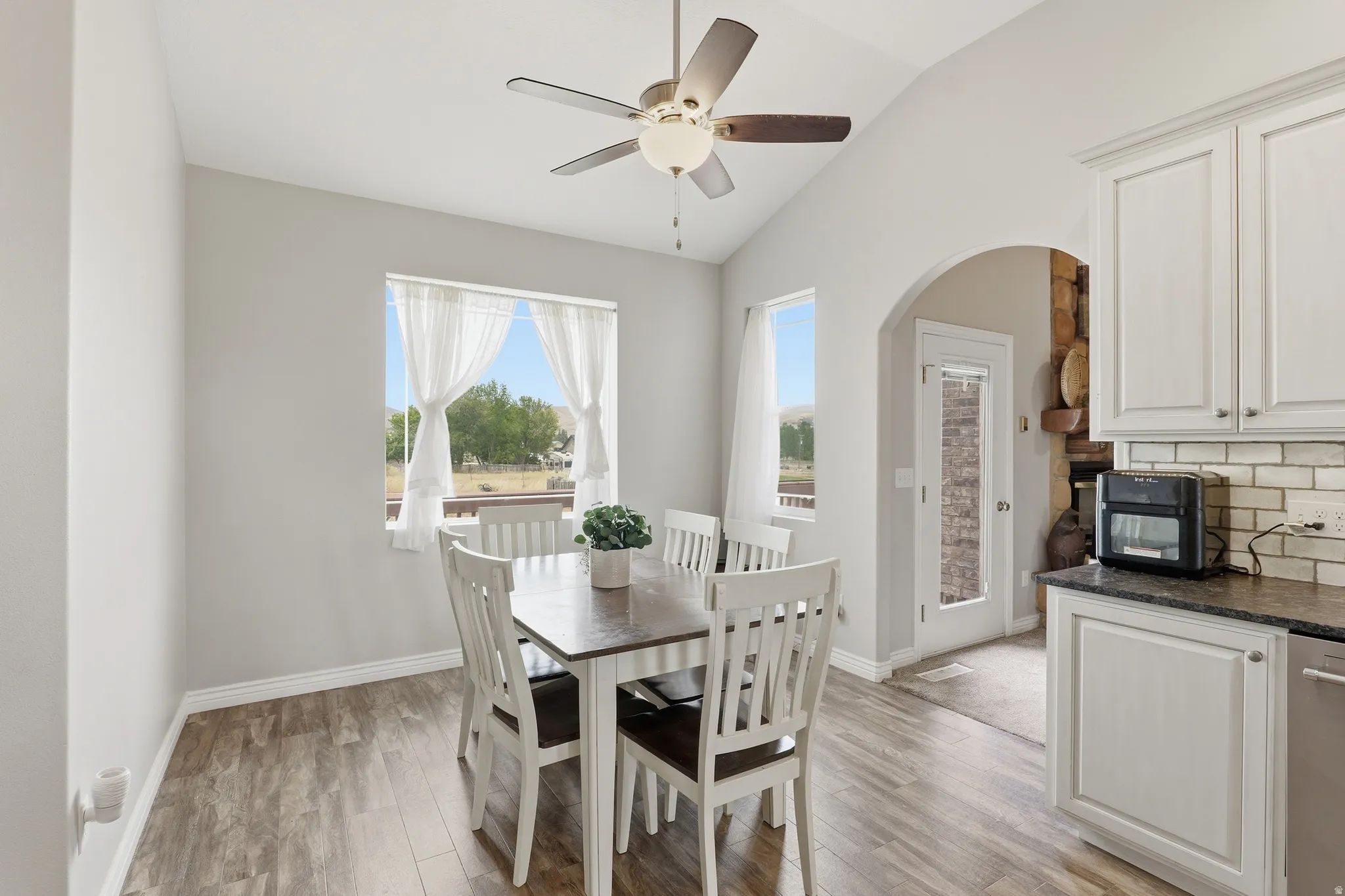 Dining area featuring vaulted ceilings, wood-finish flooring, and light-toned walls