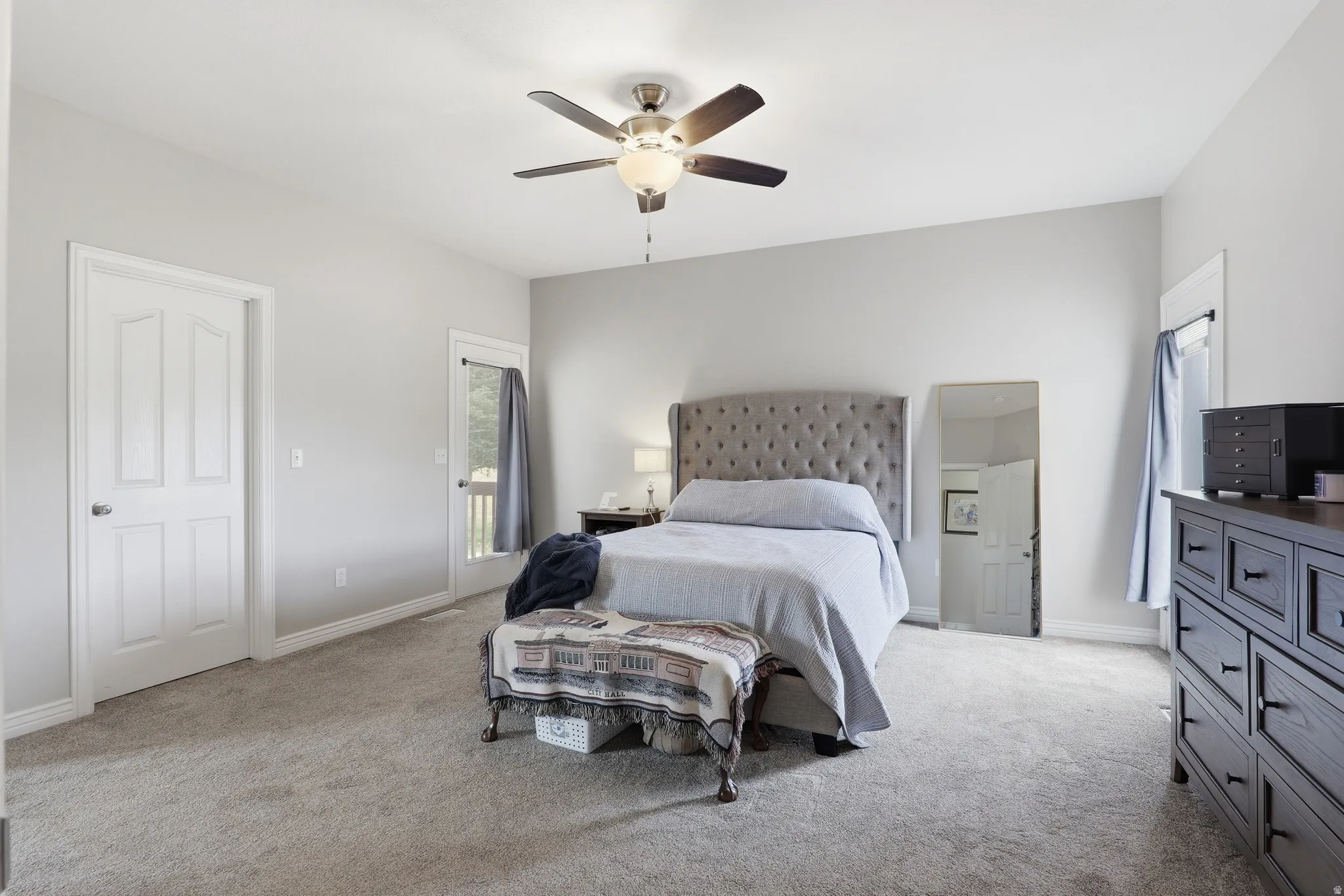 Spacious room featuring light gray walls, plush carpeting, and a ceiling fan with integrated lighting