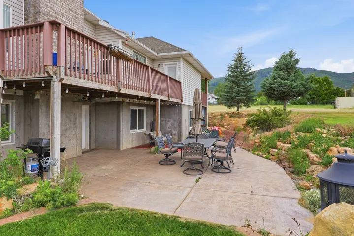 Expansive concrete patio with a tiered, natural rock landscaping feature