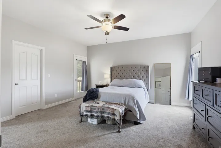 Spacious room featuring light gray walls, plush carpeting, and a ceiling fan with integrated lighting