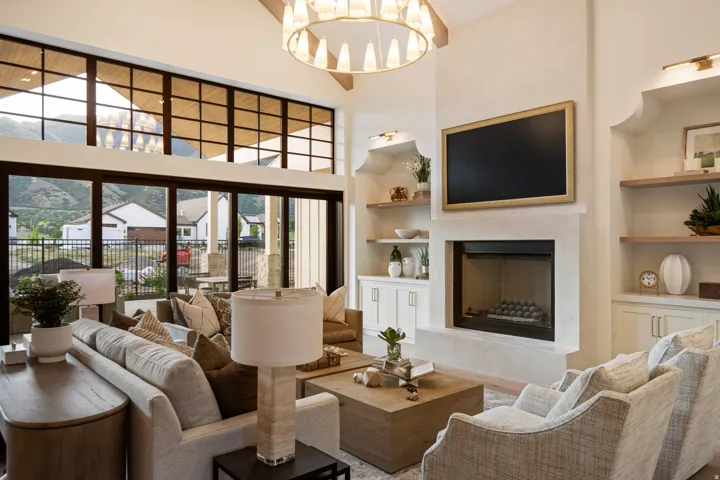 Living area featuring built in features, a premium fireplace, a high ceiling, suspended lighting, and wood finished floors