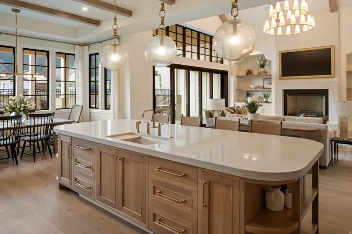 Kitchen with built in shelves, beamed ceiling, light wood-style floors, light wood finish cabinets, and a center island with sink
