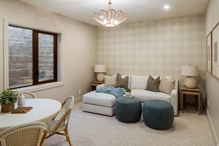 Living room featuring wallpapered walls, suspended lighting, and carpet floors