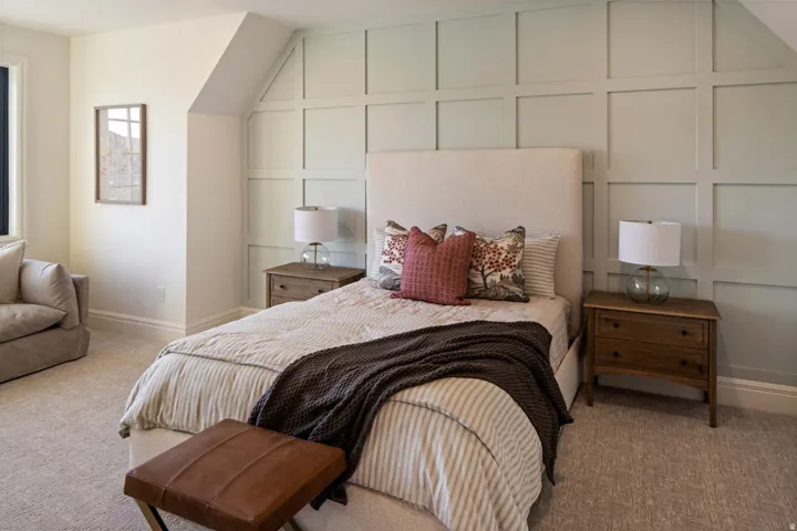 Bedroom with a decorative wall and light colored carpet