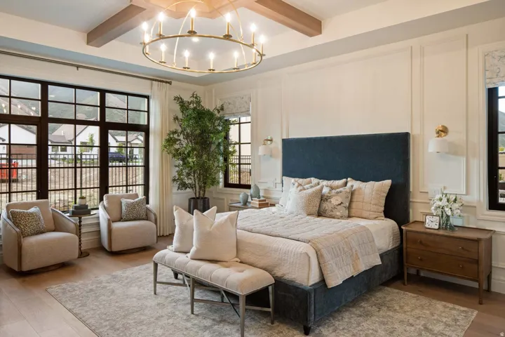 Bedroom with wood finished floors, hanging lights, beamed ceiling, and a decorative wall
