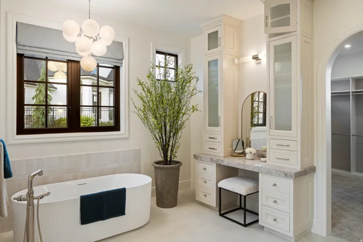 Bathroom featuring a soaking tub, a walk in closet, tile walls, hanging lights, and light tile patterned floors
