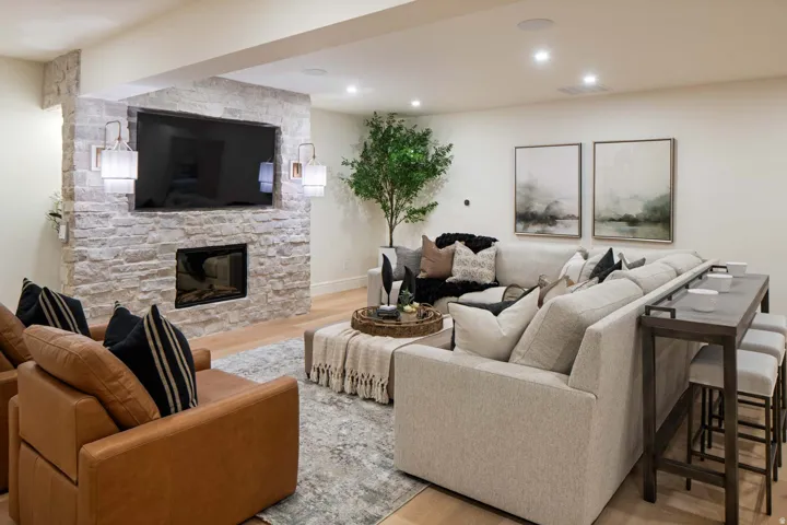 Living area featuring light wood-type flooring, a stone fireplace, and recessed lighting
